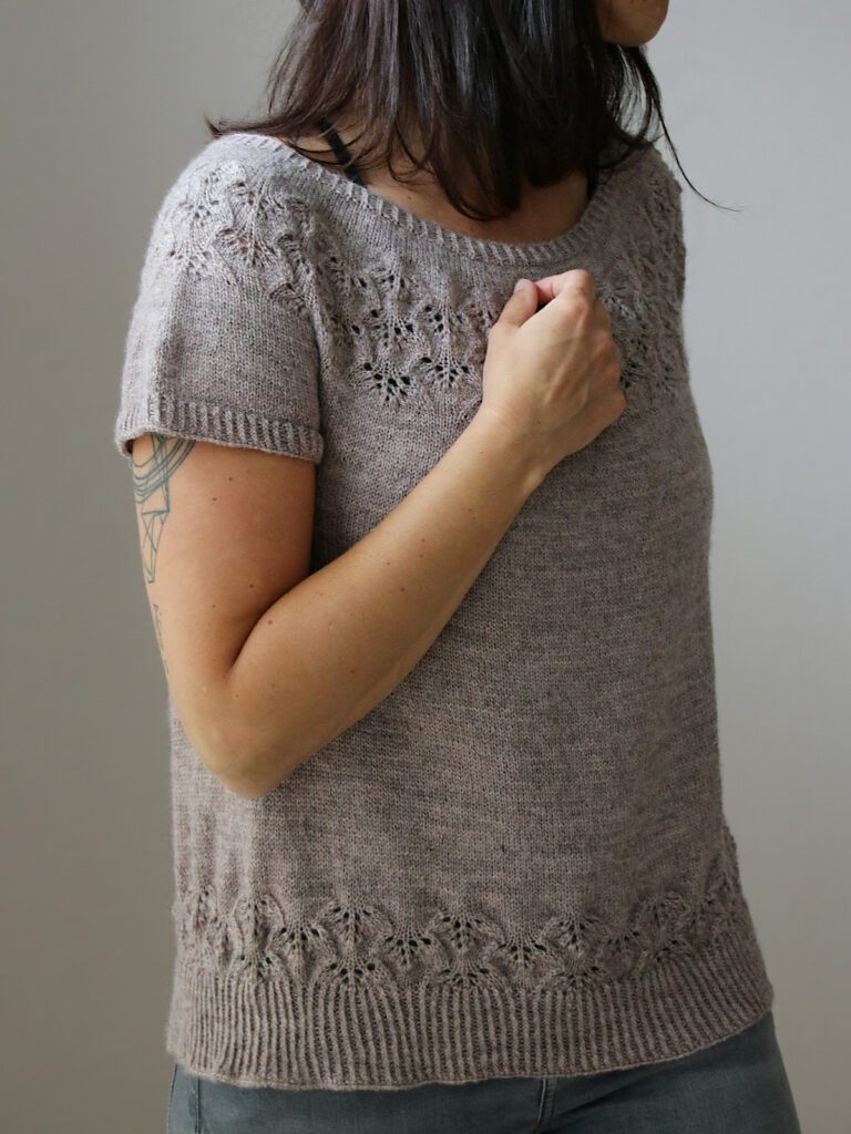 Designer Melanie Berg wears her shirt A Study in Pink. The hem and yoke are decorated with a lace pattern, the sleeves are short.