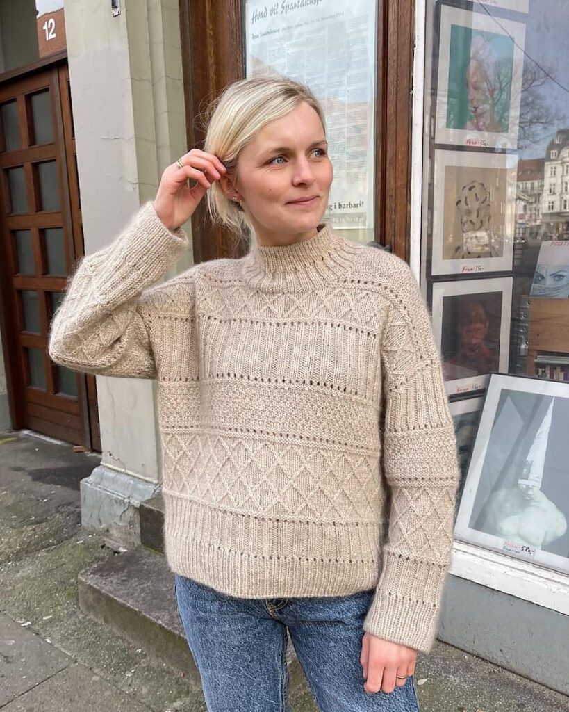 Mette wears the Ingrid sweater, which is adorned with various textured patterns.
