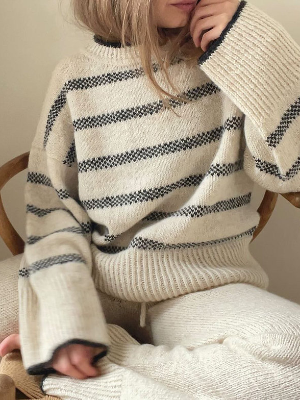 The model wears the North sweater. The sleeves are wide cut, the sweater itself is light with dark stripes.